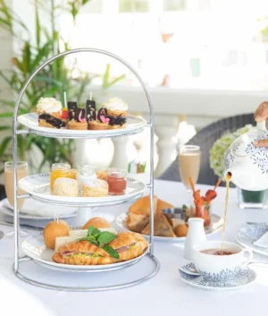 High tea for 2, short eats and snacks laind out on a tower tray with tea being poured into a cup. Location is the Verhandah restaurant at the Galle face Hotel in Colombo Sri lanka.